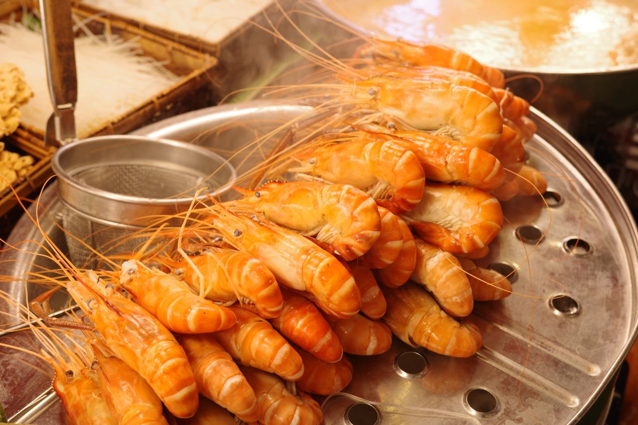 Home Close-up of freshly steamed shrimp stacked on a metal tray, ready to serve.